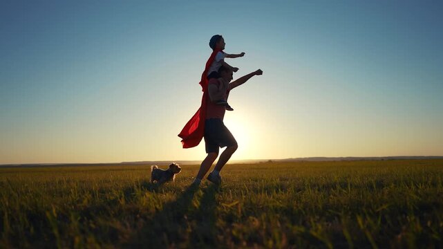 Father and son running superhero silhouette. Child family super concept. Silhouette of a superhero with his daddy and baby. Silhouette of superhero with father and son running on grass.