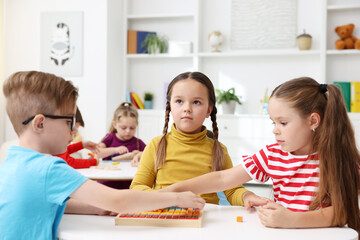 Fototapeta premium Cute children at white tables during lesson in elementary school