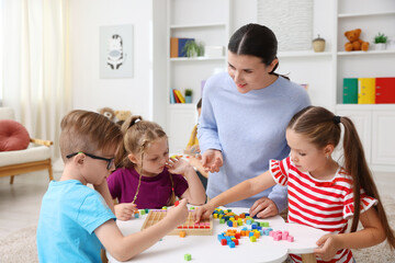 Fototapeta premium Cute children and smiling teacher at white table during lesson in elementary school