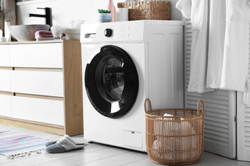 Washing machine and laundry basket near sink in bathroom. Interior design
