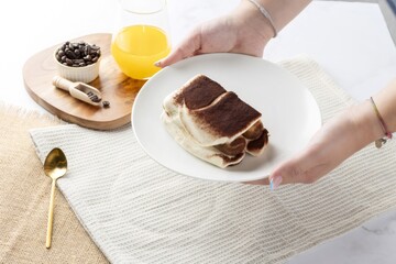 Serving tiramisu dessert with coffee and orange juice