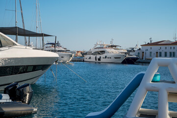 A peaceful marina scene with luxurious yachts docked under a clear blue sky, capturing the serene beauty of the waterfront at Limassol Marina