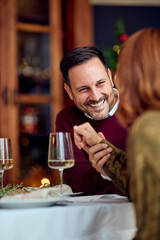 Smiling Couple Shares Warm New Year Dinner Moment Over Wine At Festive Table