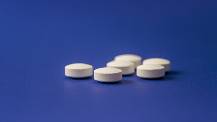 White round tablets scattered on a blue background highlighting the medication's simplicity and accessibility