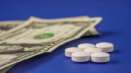 Money and pills on a blue background showing the relationship between finances and health choices