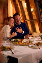 Joyful Couple At Cozy New Year Dinner Laughing Together Over Wine And Food