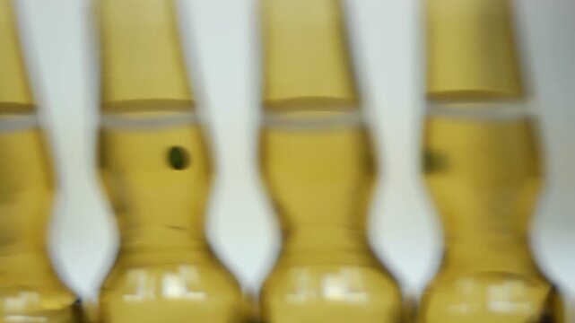 High-definition footage of an automated cleanroom assembly where glass ampoules are washed, filled with injectable medication, sterilized, and hermetically sealed. Showcases precision robotics, strict