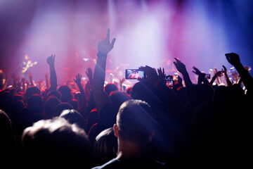 Fans raise hands at rock concert with stage lights
