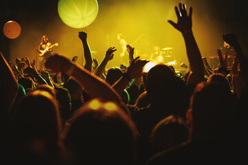 Fans cheering at concert with yellow stage balloons © 9parusnikov
