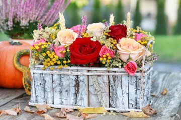 Florist at work: woman shows how to make classic floral arrangement with roses, heather, tansy and other plants in wooden box. Step by step, complete tutorial