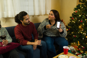 Hispanic couple having a fight over some text messages during a christmas party with friends