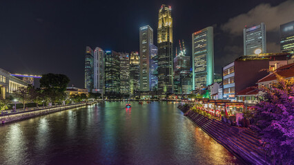 Naklejka premium Singapore quay with tall skyscrapers in the central business district on Boat Quay day to night timelapse