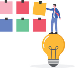 Businessman attaching a paper to a noteboard next to a lamp,
