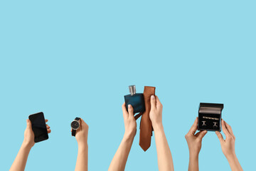 Female hands with men's tie, mobile phone, bottle of perfume, watches and cufflinks on blue background