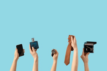 Female hands with men's tie, mobile phone, bottle of perfume, watches and cufflinks on blue...