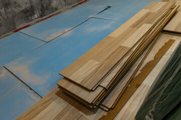 Wood laminate flooring installation on blue underlay during home renovation process