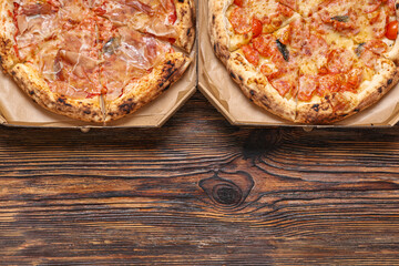 Cardboard boxes with tasty pizza on wooden background