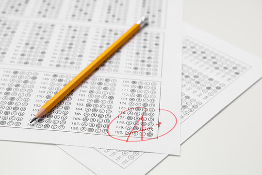 Pencil and answer sheets form of school test with results on white background, closeup