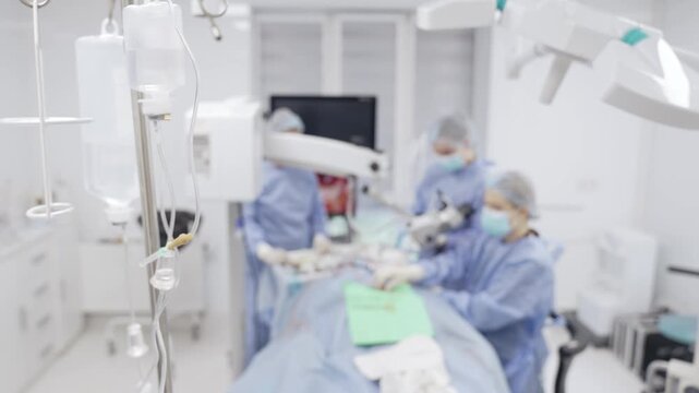 A stand with a dropper in the operating room. A surgeon is working on a tympanoplasty operation on a blurred background
