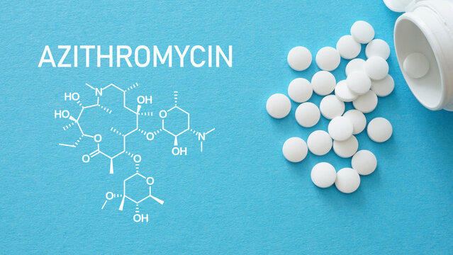 Azithromycin white medical pills spilling out of a drug bottle. Chemical structure of Azithromycin