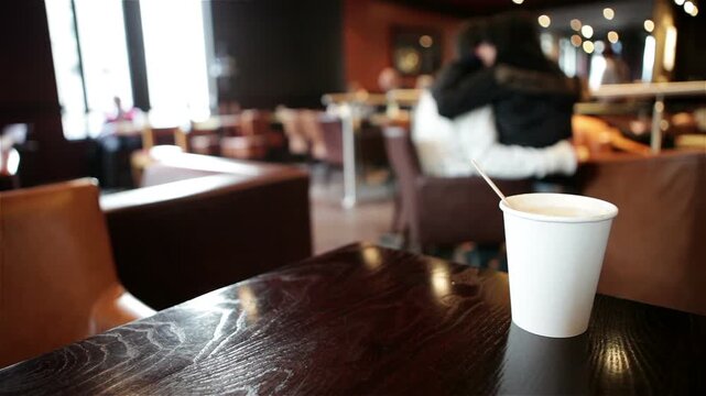 Coffee Shop interior. A candid view of the interior of a generic coffee shop with focus on the foreground white label cup on the table.