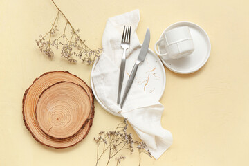 Table setting with cutlery, dishes and wooden boards on beige background
