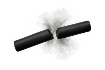 Broken charcoal stick representing separation and artistic creation, with a smudge of black powder