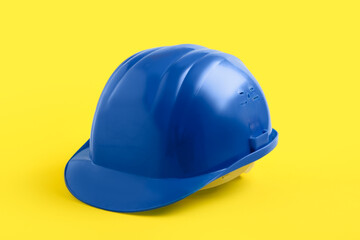 Fototapeta premium Blue hardhat on yellow background