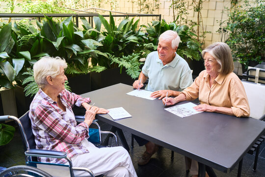 Group of seniors solving puzzles together outdoors in a retirement home garden