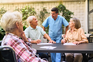 Elderly individuals with caregiver engaging in a group activity at rehabilitation center