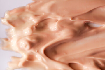 Shiny cream texture forming wave-like lines. Visual softness and refined simplicity.