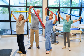 Seniors enjoying a group activity with instructor using stretching bands indoors