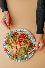 Pasta with shrimps, arugula and tomatoes isolated. Female hands with cutlery