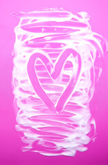 Macro closeup of smooth cream spread across pink surface. Focus on texture and detail.