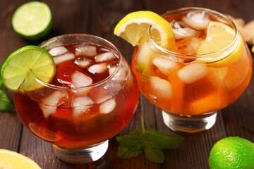 Glasses of cold tea with citrus fruit slices and mint leaves on wooden background