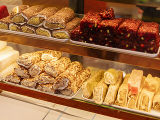 A vibrant display of traditional sweets featuring a variety of textures and colors. The showcase includes rolled confections and cubes, inviting customers to indulge in unique flavors