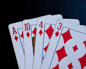 Exciting poker hand with ace, ten, four, three of diamonds on dramatic dark background, gamble on winning strategy, chance, and risk concept