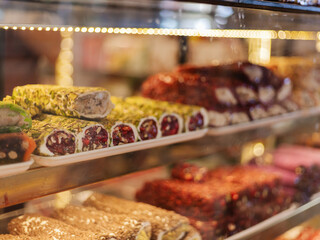 Shelves filled with an array of traditional sweets, featuring vibrant colors and textures. The display includes rolled desserts adorned with nuts and fruit, enticing customers