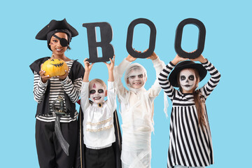 Group of children dressed for Halloween with pumpkin and word BOO on blue background
