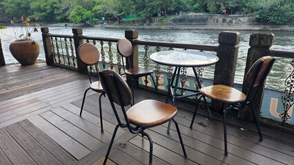 Cozy Outdoor Seating Area by the River with Empty Chairs and Table for Dining and Relaxation