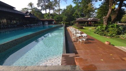 Serene Poolside with Lush Greenery and Relaxing Outdoor Seating Area near a Tranquil Resort