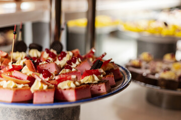 A delightful assortment of desserts is presented on a table at a lively buffet. Cakes, creams, and colorful toppings create an inviting and festive atmosphere for guests enjoying the spread