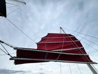 Red sail on a traditional boat against blue sky