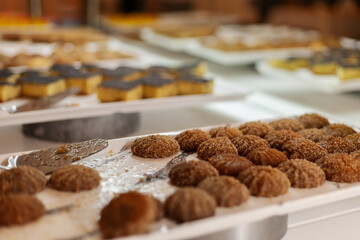 A selection of sweet treats is beautifully arranged on trays for guests to enjoy at a celebration. Different pastries and candies are presented, showcasing variety
