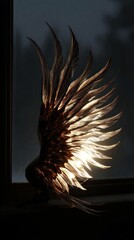 Light catches intricate, feathered wing resting on a dark sill against blurred backdrop