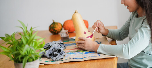 Female kid painting a pumpkin for an halloween party fest - Holidays, education and art concept - Main focus on face