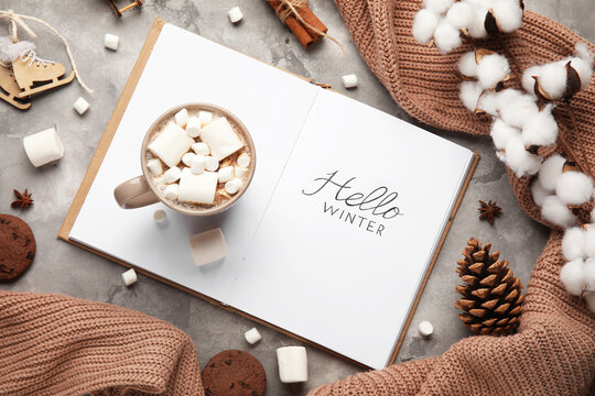 Notebook with text HELLO WINTER, cocoa, cotton flowers and sweater on grunge background