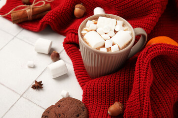 Cup of cocoa with marshmallows and sweater on white tile background, closeup. Hello winter