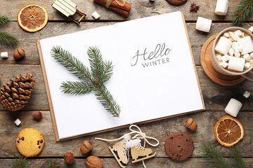 Notebook with text HELLO WINTER, Christmas branches and treats on wooden background