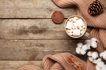 Cup of cocoa with cookie, sweater and cotton flowers on wooden background. Hello winter